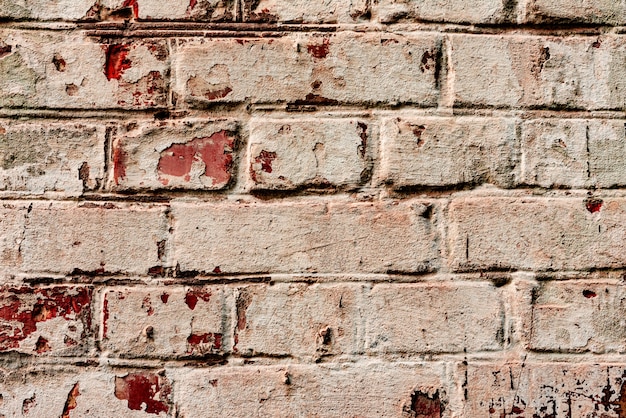 Foto trama di un muro di mattoni con crepe e graffi che possono essere utilizzati come sfondo