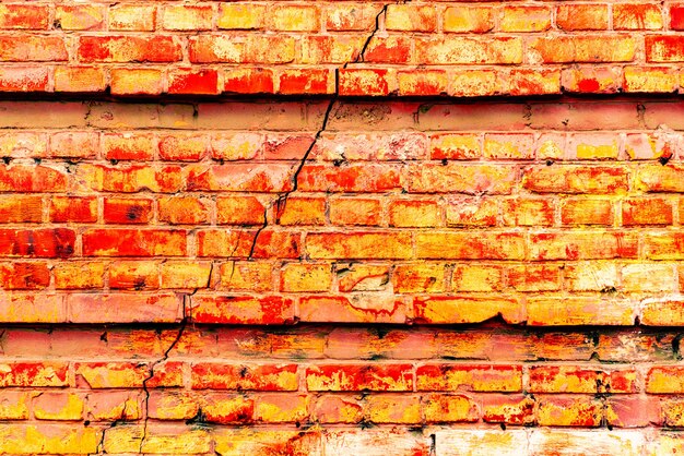 Foto texture di un muro di mattoni con crepe e graffi che può essere utilizzato come sfondo