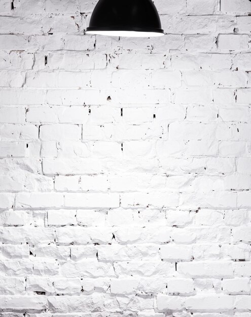 Photo texture of brick whitewashed wall illuminated with lamp on top