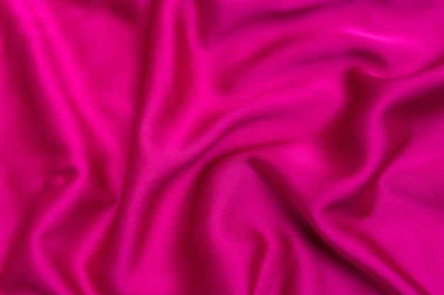 Texture of bright pink tissue silk or satin Fabric fuchsia or crimsoncolored color Abstract background
