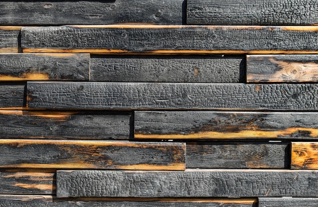 Texture of burnt boards. Blackened charred wood planks with light veins. Burnt scratched hardwood surface.