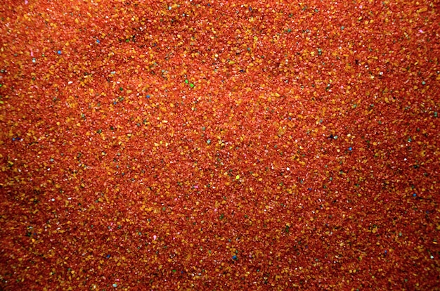 Texture of a colored granular sand close up. Red grains