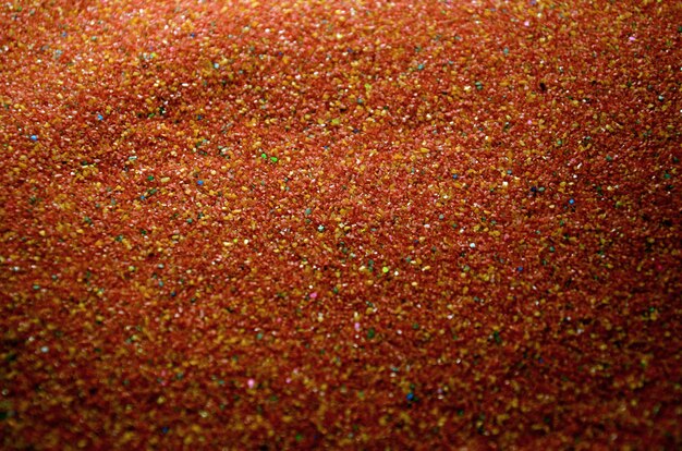 Texture of a colored granular sand close up. Red grains