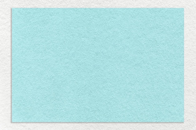 Texture of craft light blue color paper background with white border macro Structure of vintage turquoise cardboard