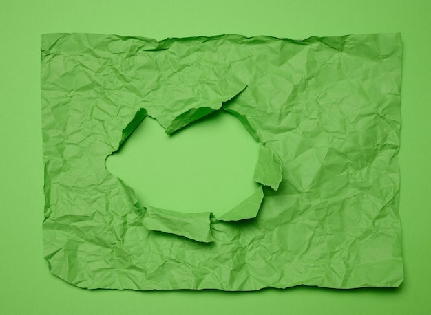 Photo texture of crumpled green paper with torn hole and green background template for designer