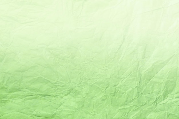 Texture of crumpled light green wrapping paper with gradient closeup Light olive old background