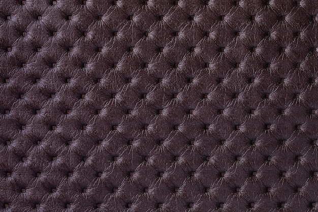 Photo texture of dark brown leather background with capitone pattern, macro. purple textile of retro chesterfield style.