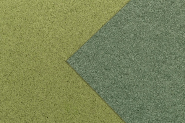 ダークグリーンとオリーブの紙の背景のテクスチャー半2色矢印マクロカーキクラフト板紙の構造