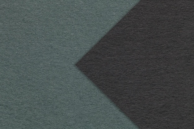 Texture of dark green paper background half two colors with black arrow macro Structure of craft teal cardboard