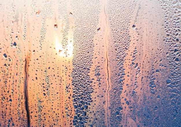 texture drops on the glass on the background of the dawn of the sun bright blueorange in colors