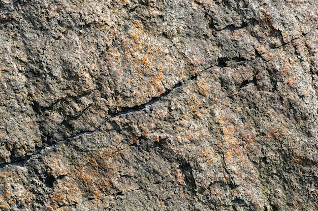 Foto texture di roccia granitica. superficie di pietra incrinata dagli agenti atmosferici. primo piano della superficie in granito. concetto di colore della terra