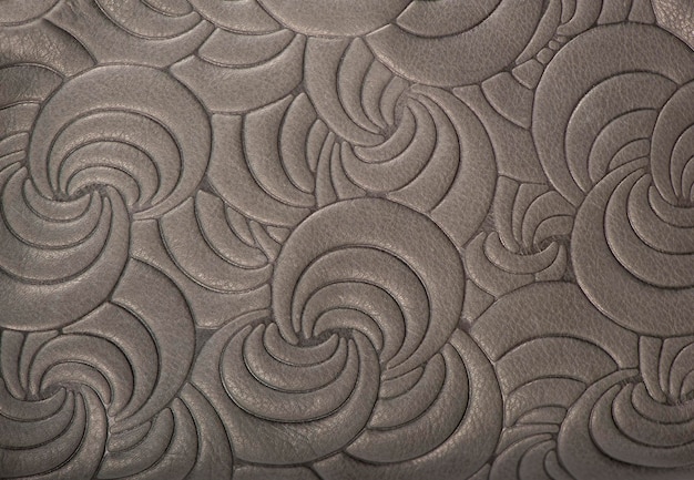 Photo texture of gray genuine leather with embossed floral trend pattern closeup