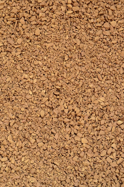 Texture of ground coffee in the form of many small pebbles of dark brown color