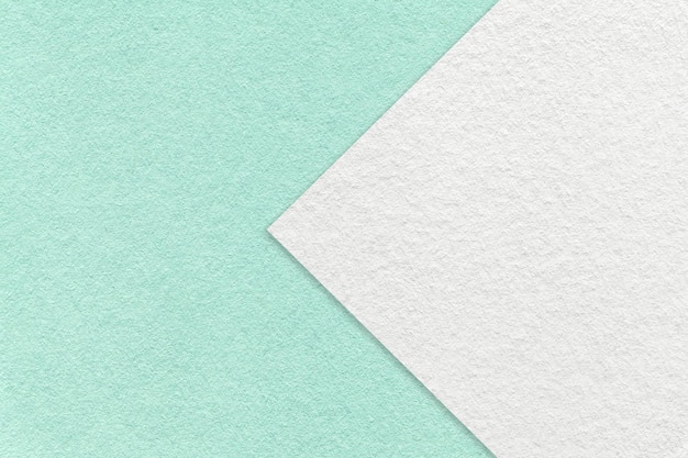 Texture of light turquoise paper background with white arrow macro Structure of craft mint cardboard