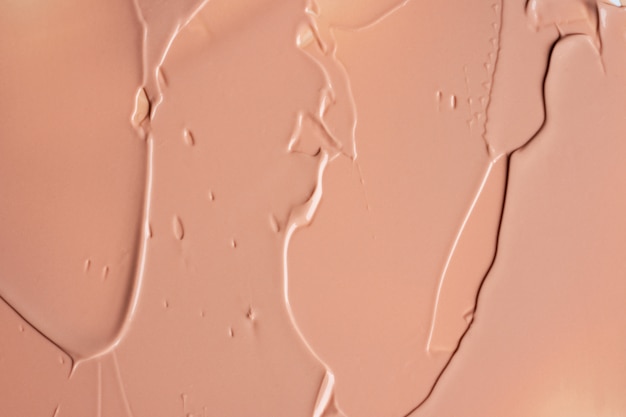 Photo the texture of liquid beige foundation blur cream background of make up. acrylic smears.