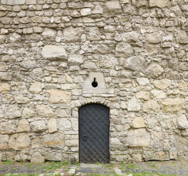 Struttura del muro di pietra medievale e della vecchia porta di metallo