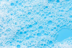 Фото Текстура белой пены на синем фоне очищающий мусс для лица или пена для ванны или стиральный порошок крупным планом