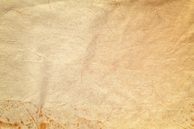 Texture of old beige paper with coffee stain, crumpled background. Vintage brown grunge surface backdrop.