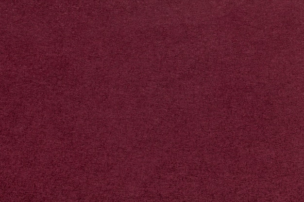 Texture of old dark red paper closeup. structure of a dense cardboard. the maroon background.