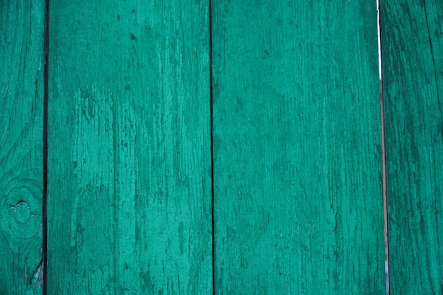 Texture of an old fence made of wooden boards painted green color closeup