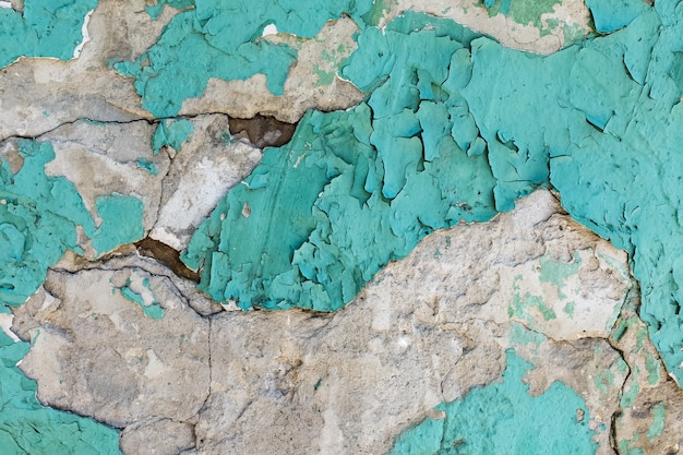 The texture of an old plastered wall with peeling blue paint Natural background and pattern