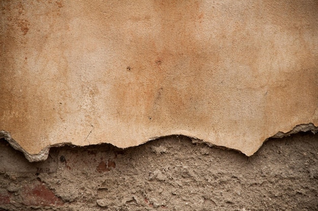 texture of an old ragged wall background of old bricks and cracks in plaster yellow and brown tones