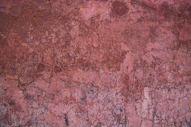 오래된 소박한 벽의 질감은 분홍색 스투코로 덮여 있습니다.