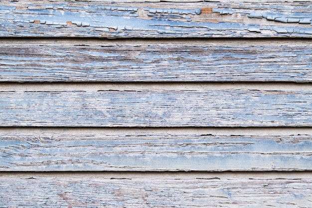 Texture of old shabby wood planks with cracked blue paint. Vintage background with knots holes.