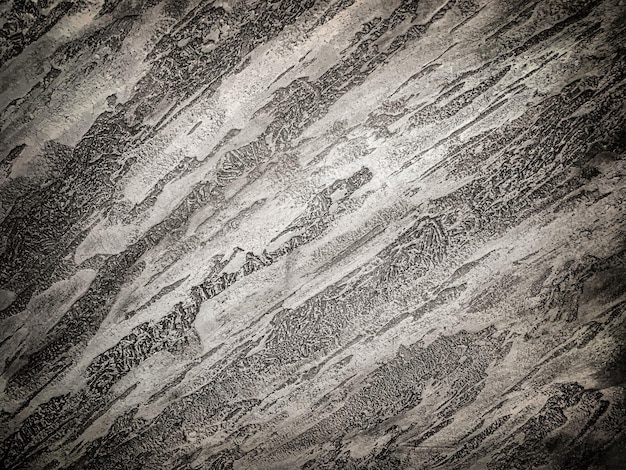 Texture del vecchio muro con intonaco decorativo colori grigio scuro. Fondo concreto incrinato di lerciume con la scenetta. Superficie di pietra astratta dello stucco, primo piano.