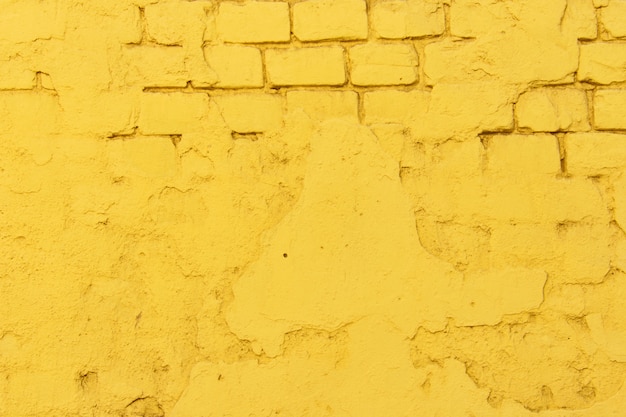 セメントとコンクリートの縫い目で古い黄色のレンガの壁の表面のテクスチャ