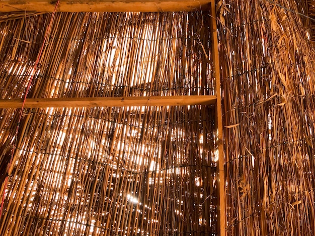 The texture of an orange brown natural dry straw shimmered in the sun roof of a thatched old