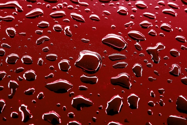 Texture of rain droplets on red background, water drops surface.
