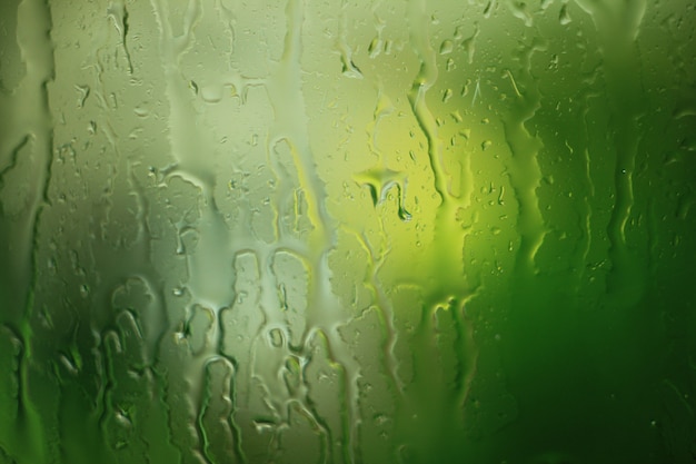 Photo the texture of the rain drops on the window glass on green background