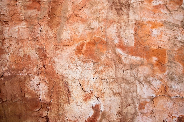 The texture of a red concrete wall with cracks and scratches can be used as a background