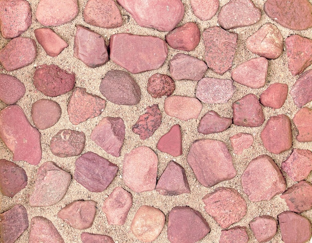 Texture of red river stones on the sand