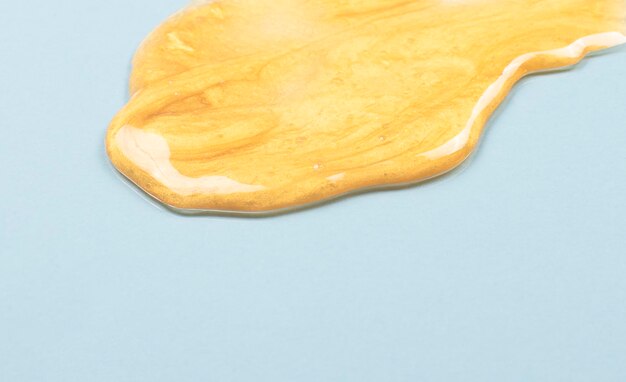 Texture of serum or face gel Golden cream for skin care on a light blue background Golden cosmetic face mask