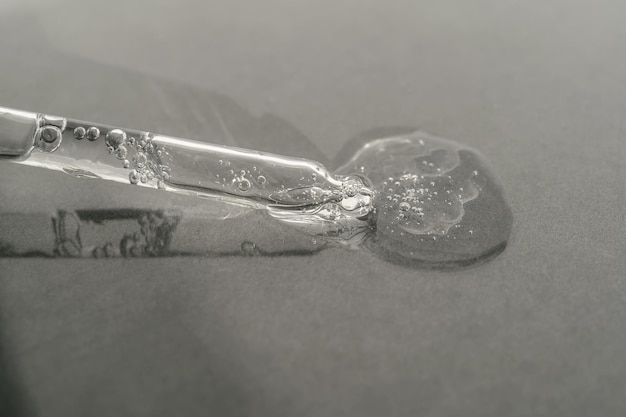 The texture of serum or oil with a pipette on a grey background
