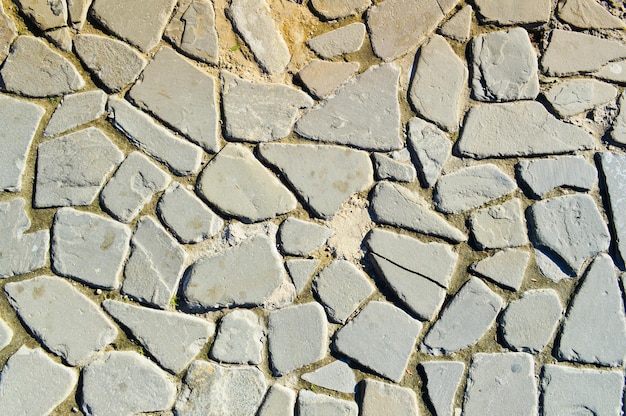 The texture of the stone road pavement walls of large gray old medieval round strong stones