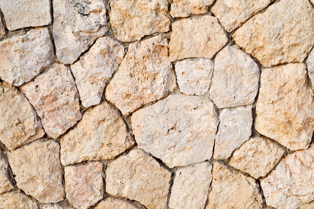 Текстура каменной стены дорог из камней, кирпичей, булыжников, плитки с песчаными швами серого древнего