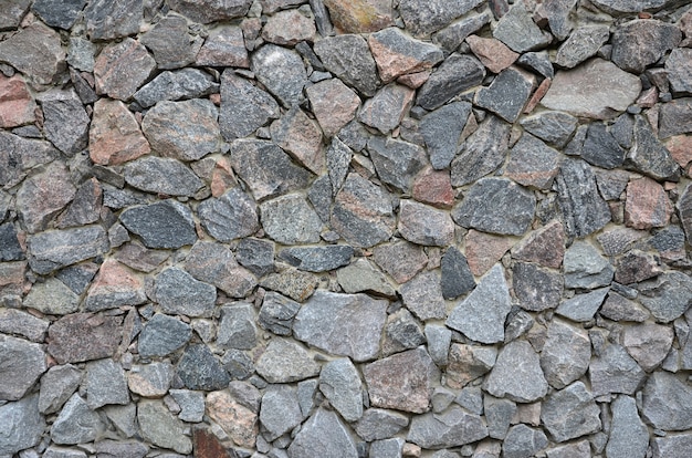 The texture of a strong stone wall of many concreted stones of various shapes