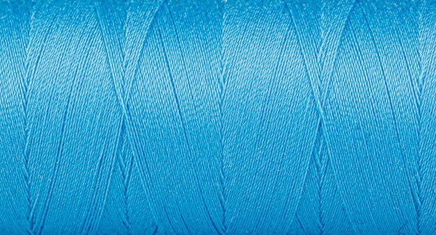 Texture of threads in a spool of blue color on a white background