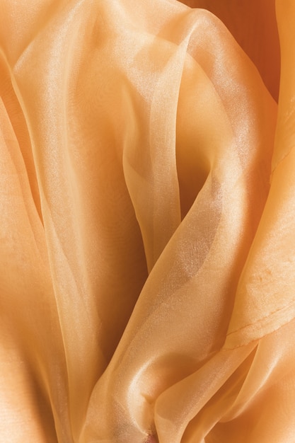 Photo texture of transparent pastel orange crumpled fabric