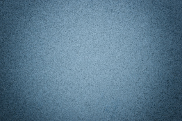 Texture of vintage navy blue paper background with matte vignette. Structure of denim kraft cardboard with frame.