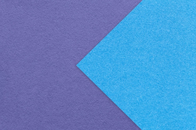 파란색 화살표 매크로가 있는 바이올렛 종이 배경 절반 두 가지 색상의 질감 매우 골판지 공예의 구조