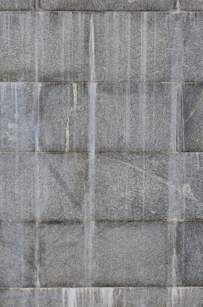 La trama di un muro di grandi piastrelle di granito che sono coperte da strisce bianche quando esposte all'umidità