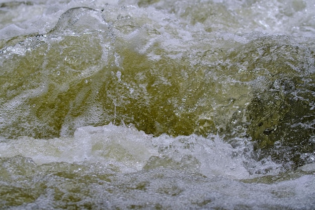 Texture of water in a natural state in a river when splashing against the stones