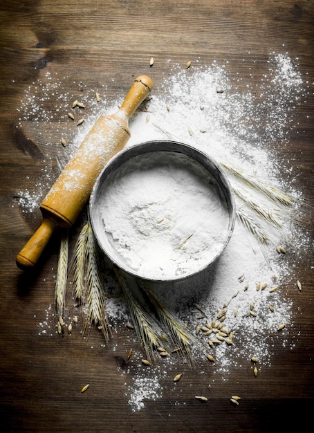 Photo texture wheat flour with a sieve and rolling pin