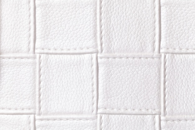 Texture of white leather background with square pattern and stitch, macro. Abstract from textile with geometric shape.