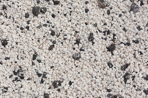 Texture of white sand with pebbles. Close-up.