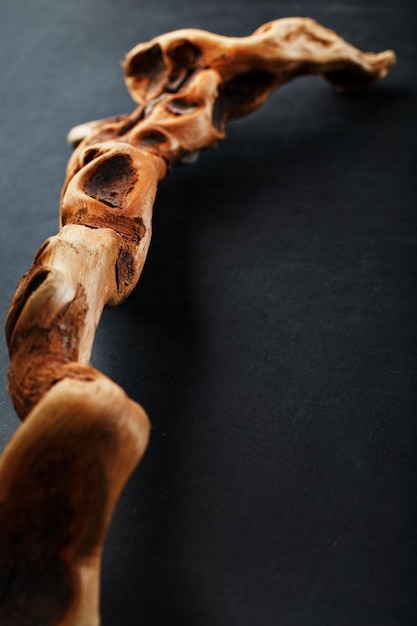 Textured curved Wooden snag of brown color with texture on a black background. Decorative wooden element, close-up, minimalism.